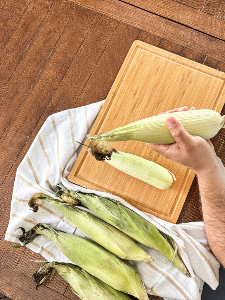 Removing the outer layer of the corn husks to get them ready for grilling.