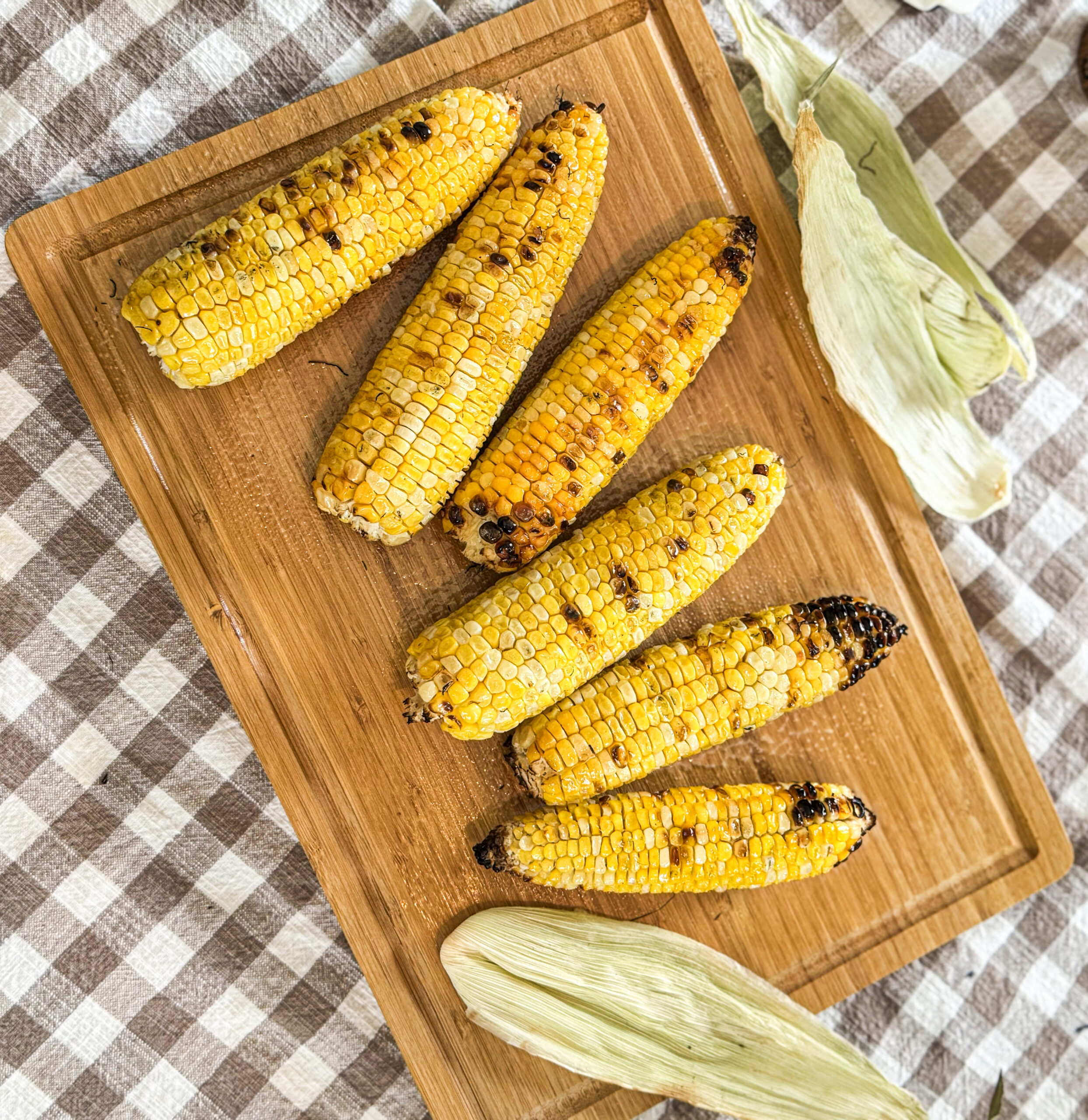 Delicious, charred grilled corn over a cutting board.