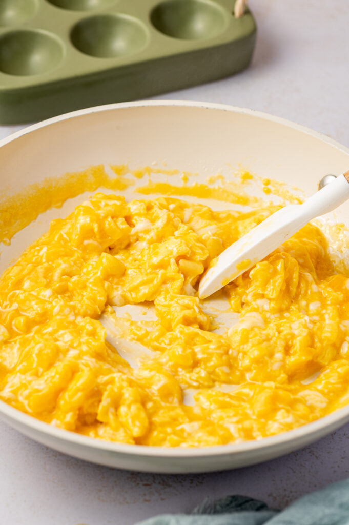 Using a spatula to mix scrambled eggs on a skillet.