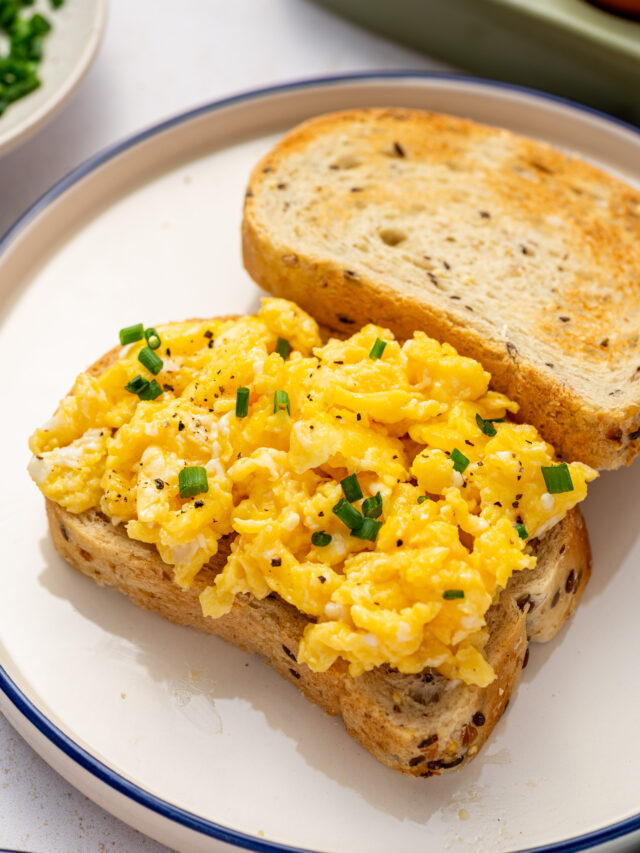 Restaurant-style scrambled eggs on toast with chives as garnish.