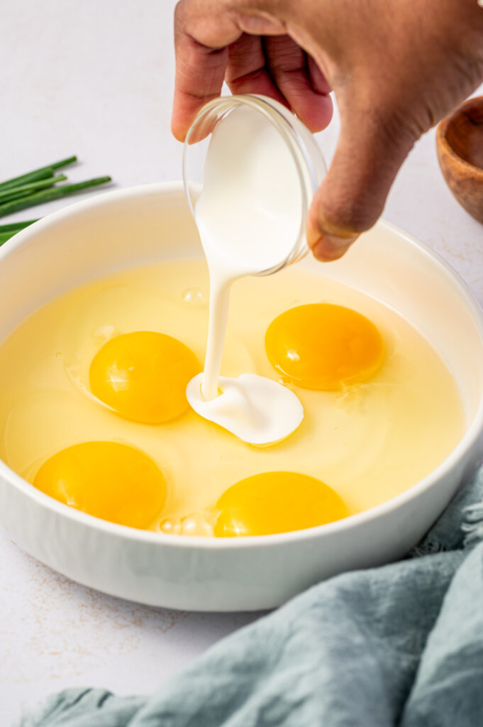 Adding heavy cream to a bowl of egg yolks.