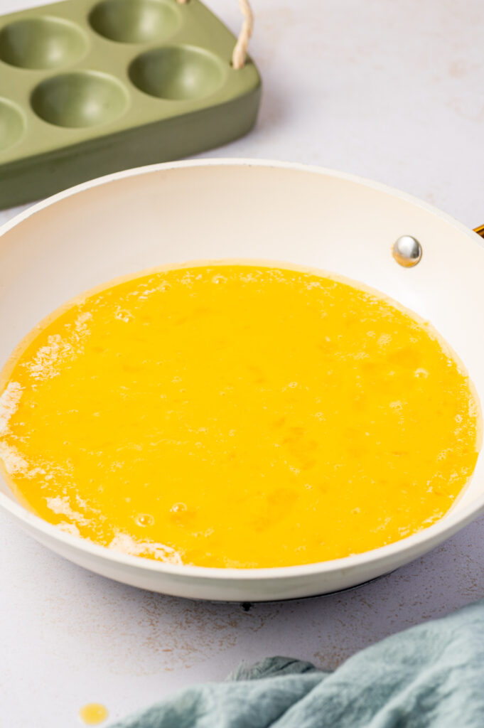 A white skillet of whisked eggs.