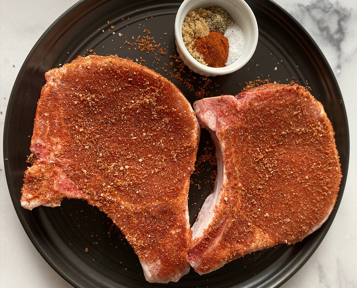 2 bone-in pork chops ready to be made in the oven.