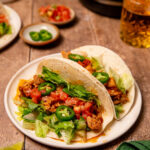 Instant Pot chicken tacos on a white plate loaded with toppings.