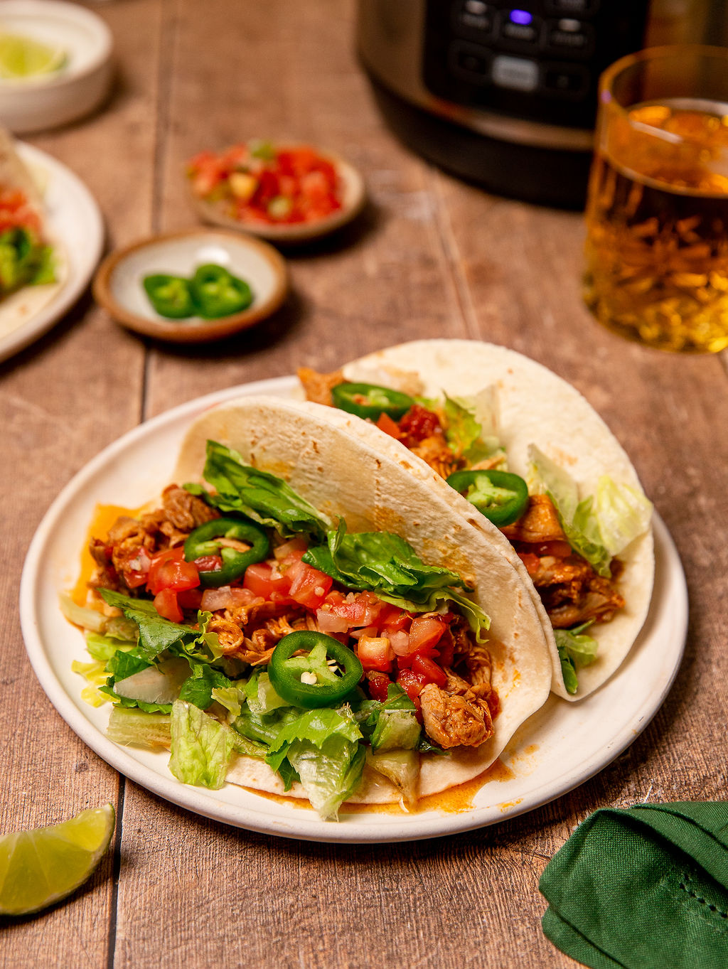 Instant Pot chicken tacos on a white plate loaded with toppings.