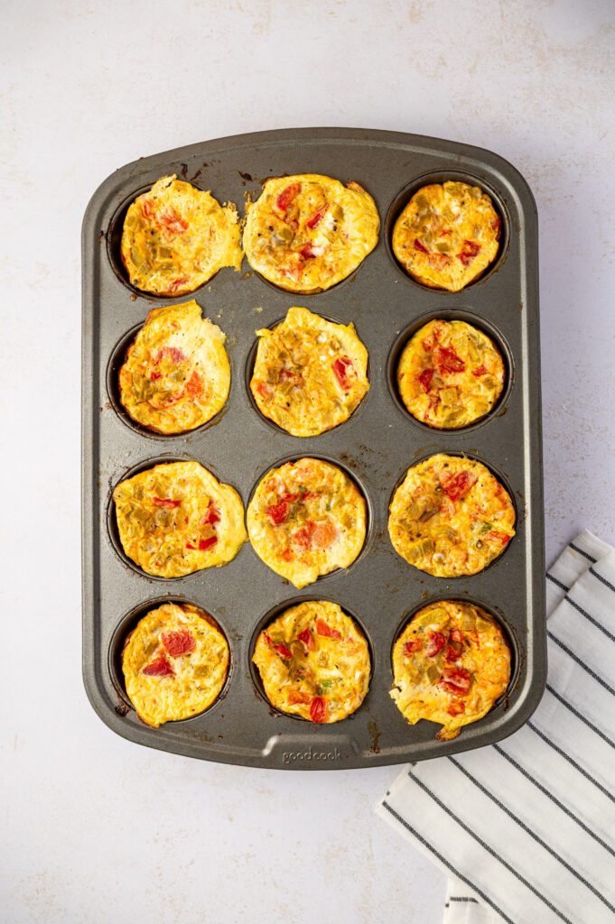 Southwest scrambled egg bites in a muffin tin with tomatoes, peppers, and green chilies fresh out of the oven.
