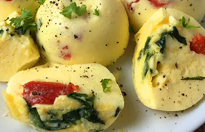 Egg bites from an instant pot loaded with roasted red peppers and fresh spinach. 
