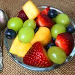A bowl of fruit salad containing strawberries, grapes, pineapple and blueberries.