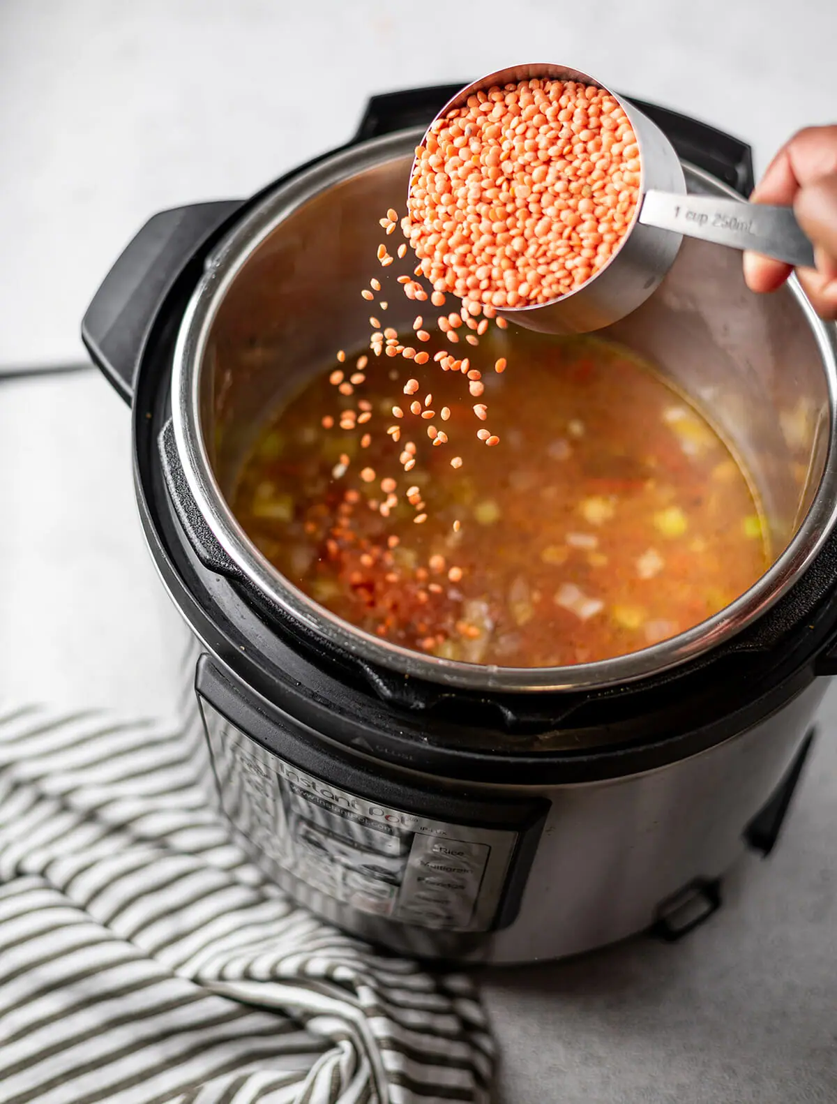 Adding split red lentils to an Instant Pot to make red lentil soup.