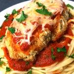 Close up of oven baked chicken parmesan recipe over spaghetti.