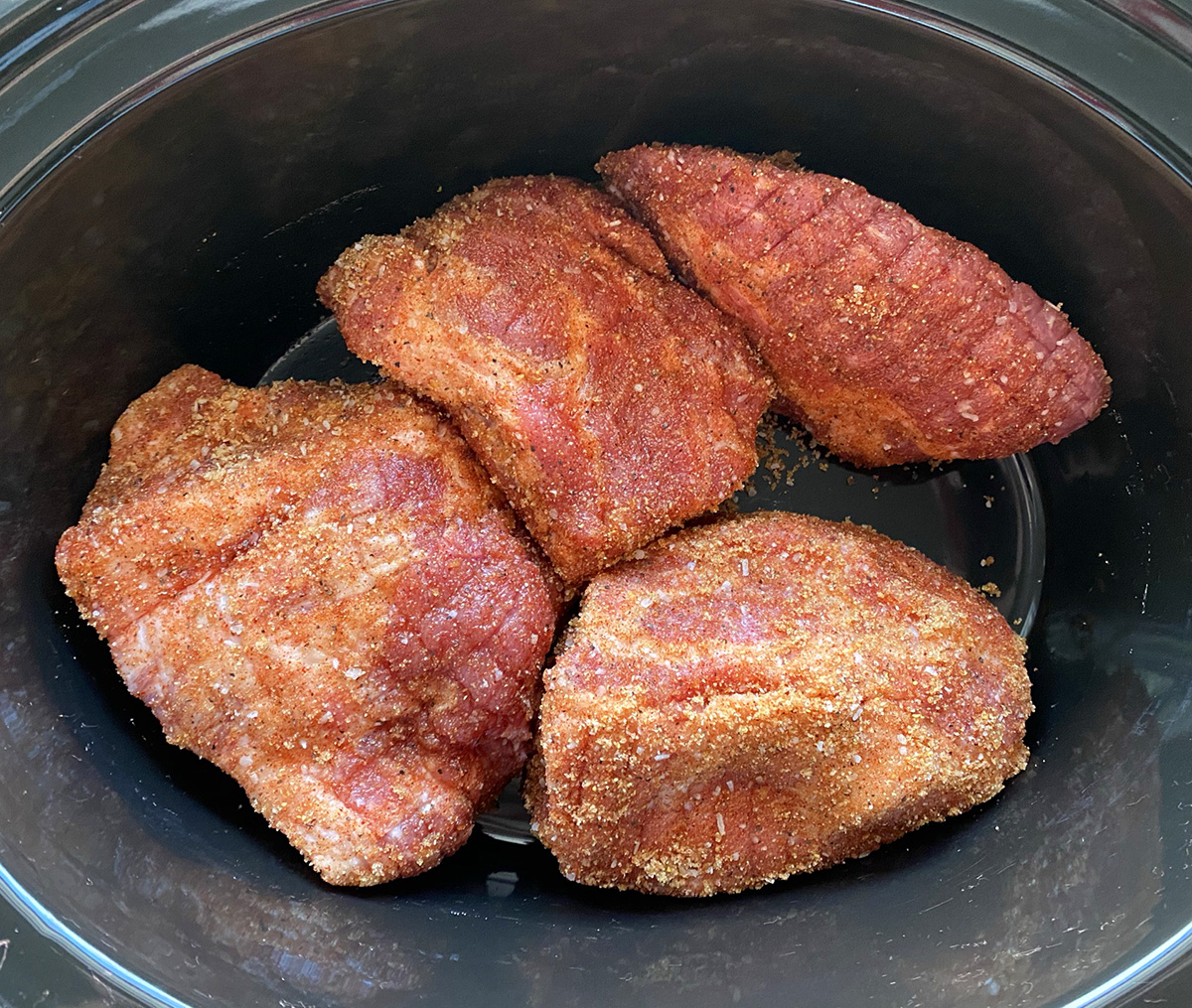 Seasoned pork chunks in a slow cooker.