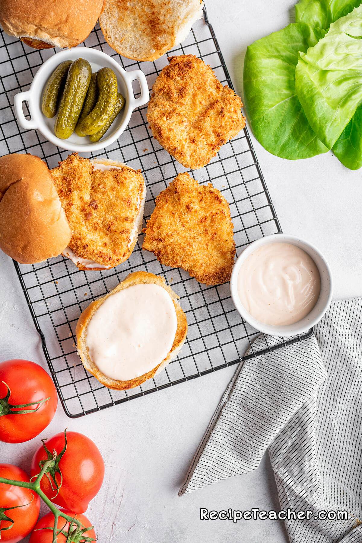 Assembling a delicious air fryer buttermilk spicy chicken sandwich with spicy mayo spread.
