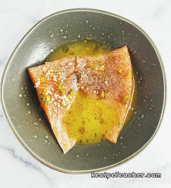 Marinating salmon filets with orange juice, lime juice and garlic.