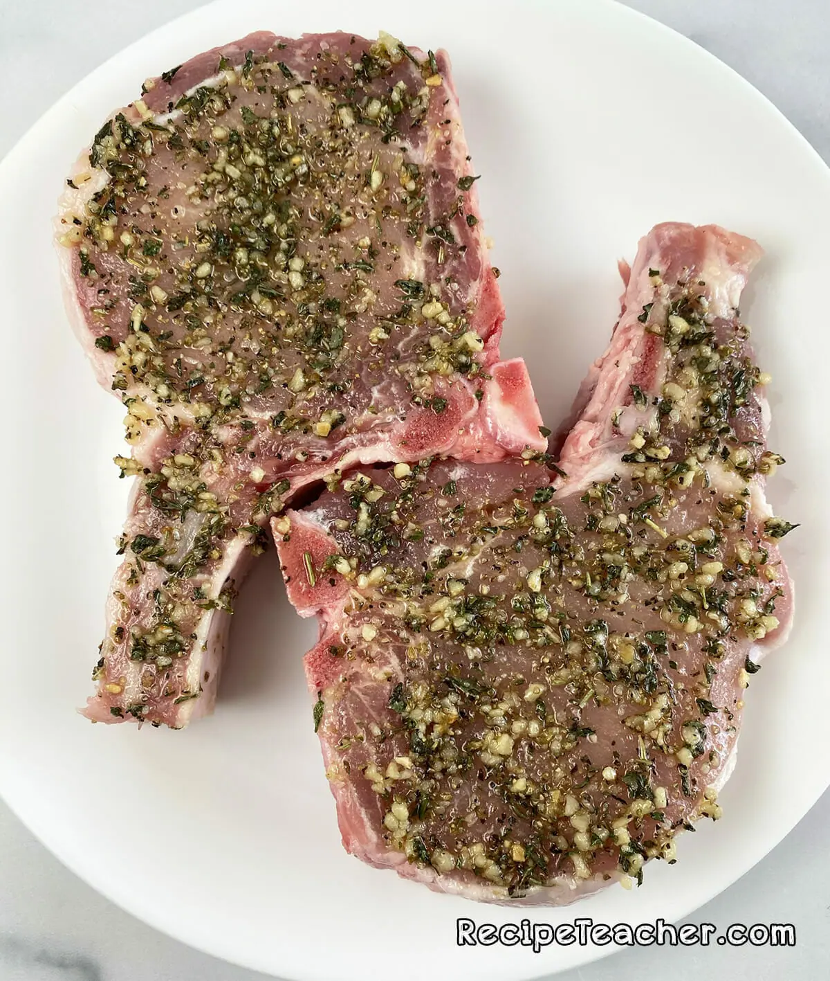 Recipe for thick and juicy air fryer pork chops. Pork chops are seasoned and ready for the air fryer. 