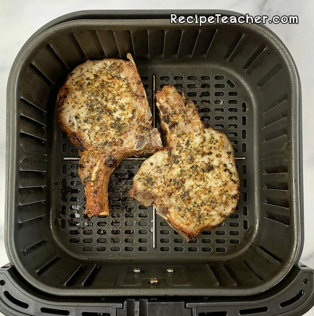 Seasoned thick and juicy pork chops coming out of the air fryer.