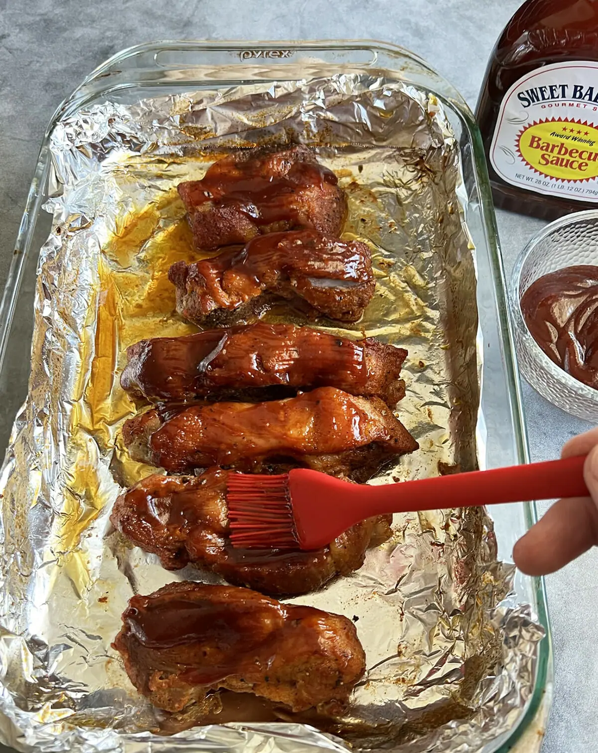 Brushing barbecue sauce onto country style ribs