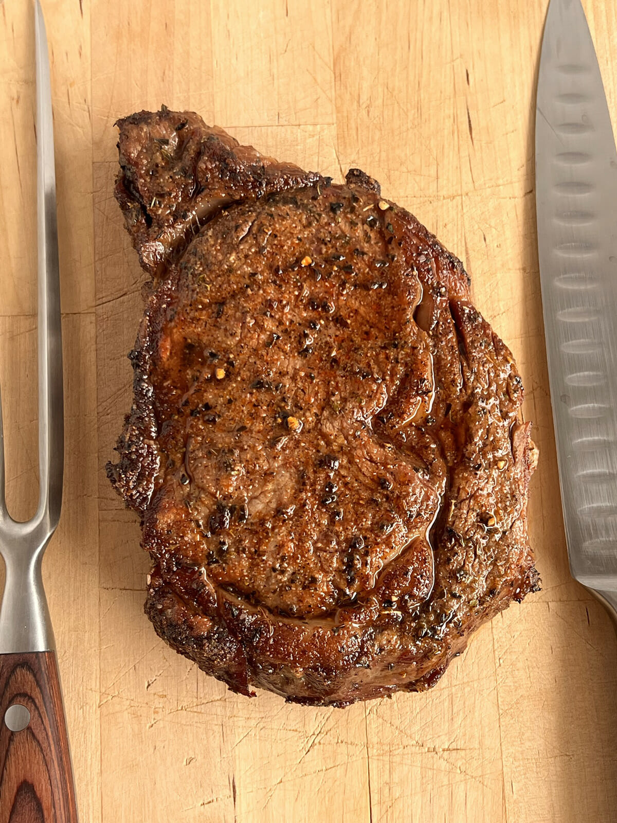 Air fryer ribeye steak resting on a cutting board.