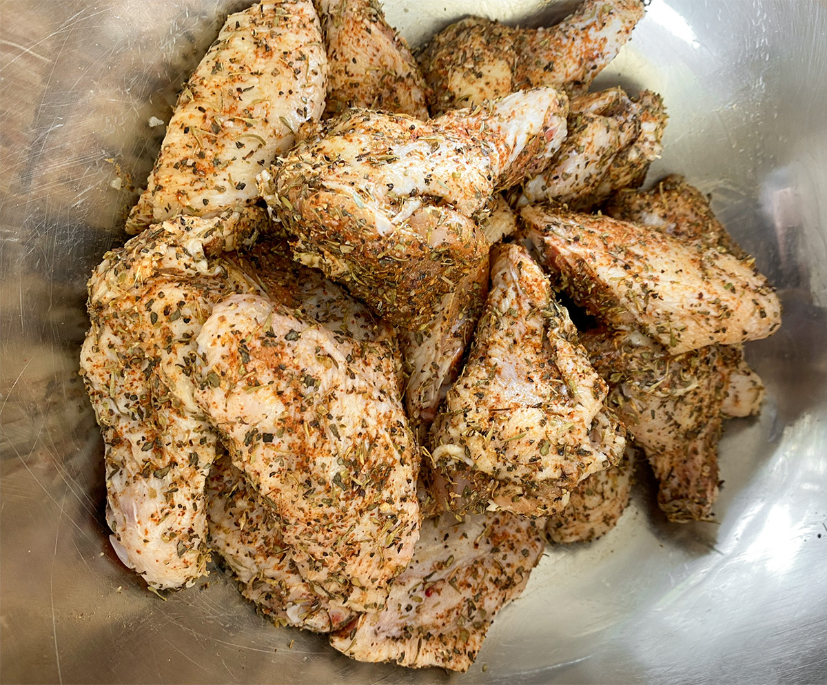 Raw, seasoned chicken wings in a bowl ready to be air fried.