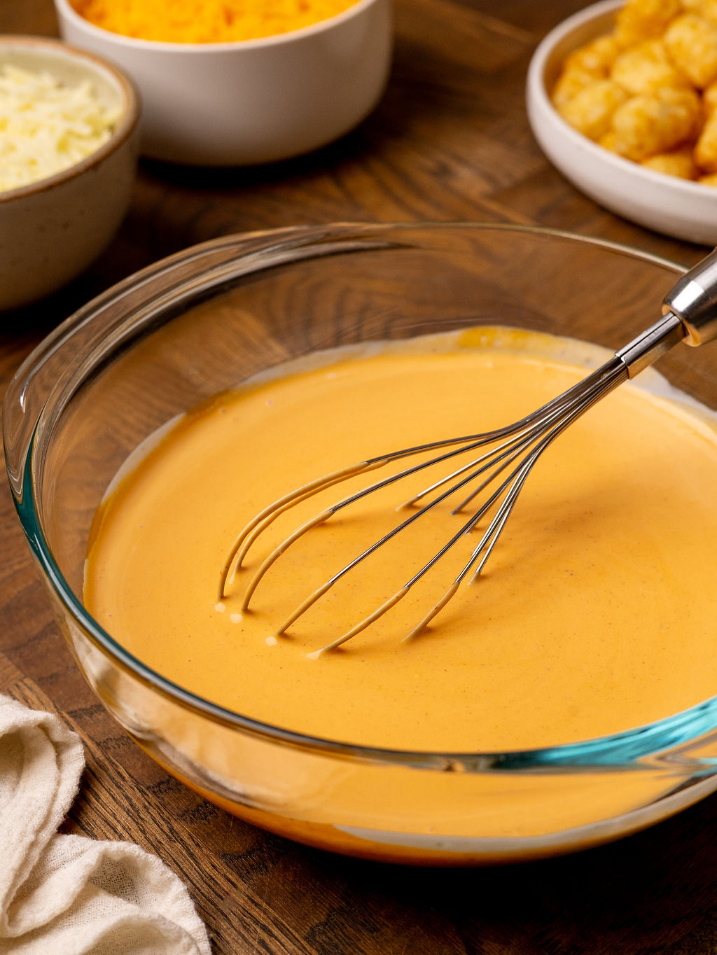 Whisking buffalo sauce in a glass mixing bowl.
