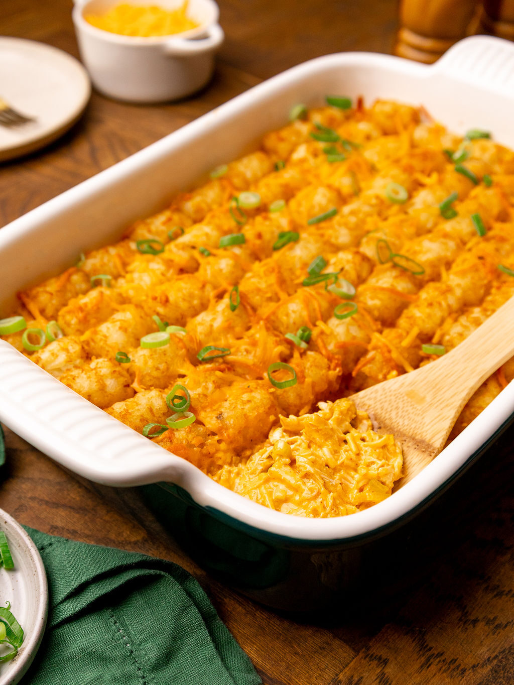 A spatula taking a slice of buffalo chicken tater tot casserole out of a baking dish.