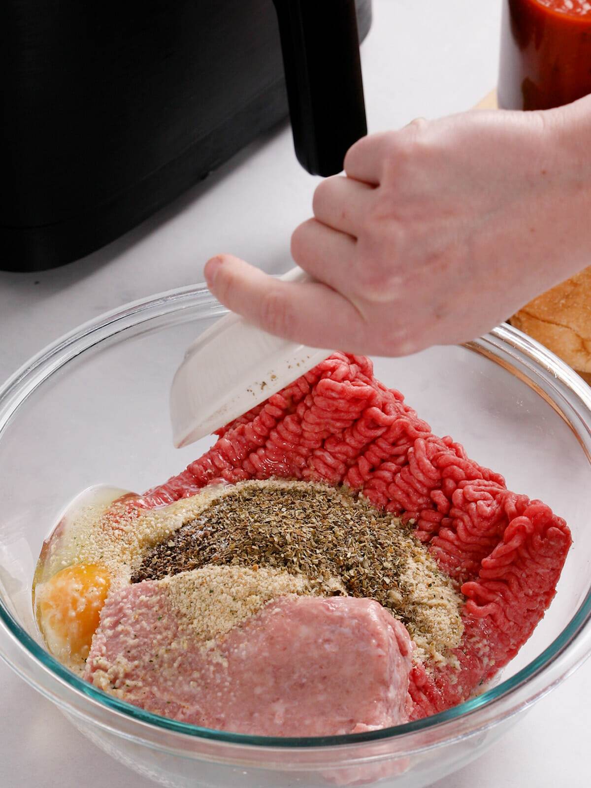 Adding all the ingredients together to make air fryer meatball sandwiches.