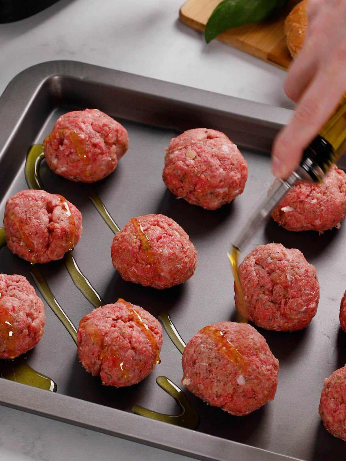 Drizzling olive oil on meatballs for our air fryer meatball sandwiches recipe.
