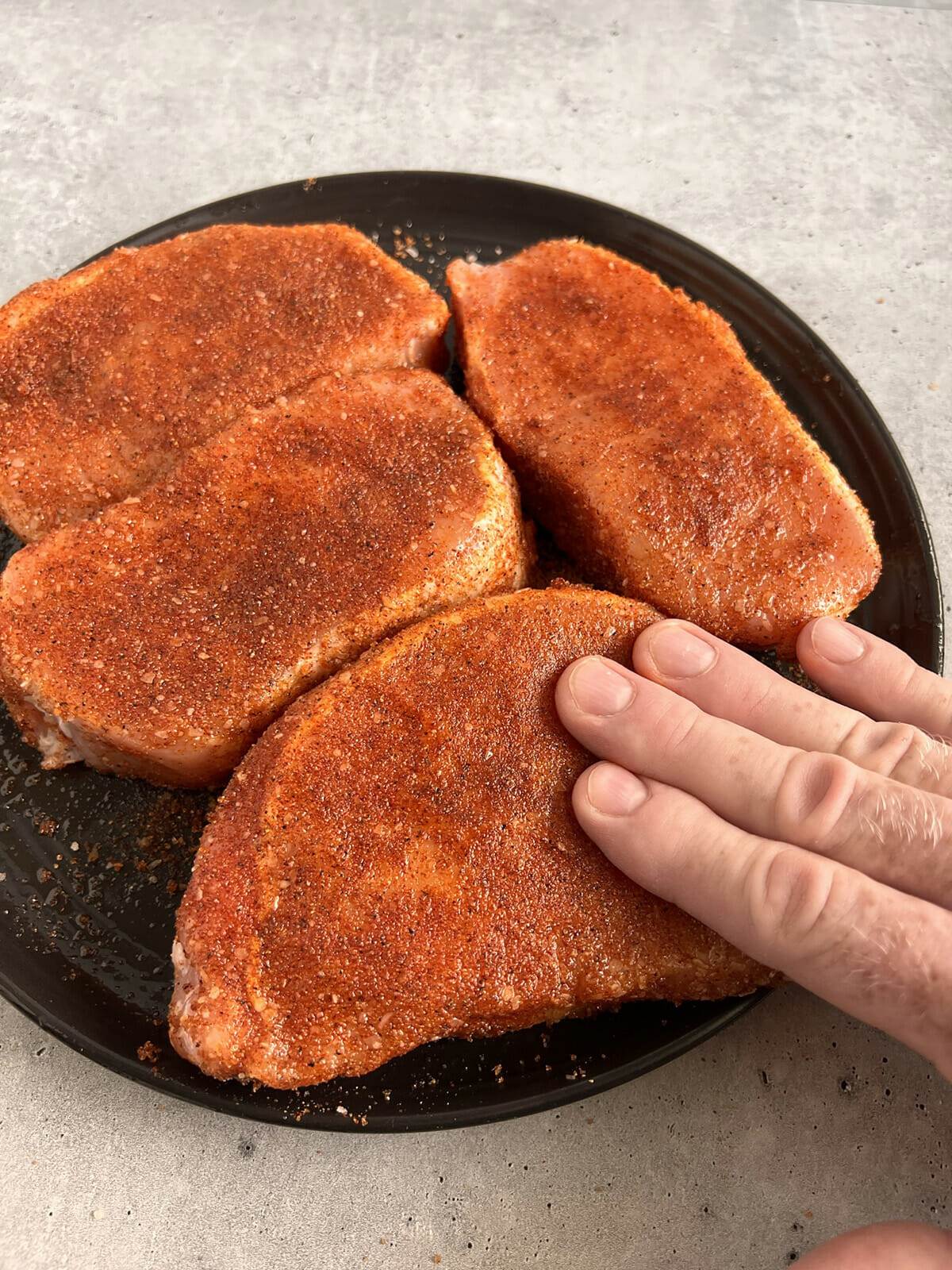 Seasoned boneless pork chops ready to be cooked in the oven.