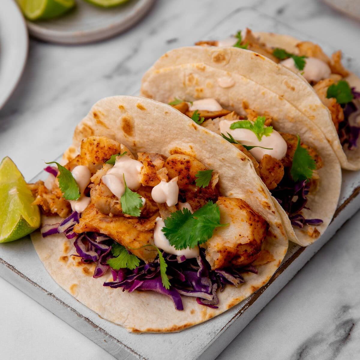 Fish tacos topped with a lime crema sauce made with an easy sheet pan oven recipe.