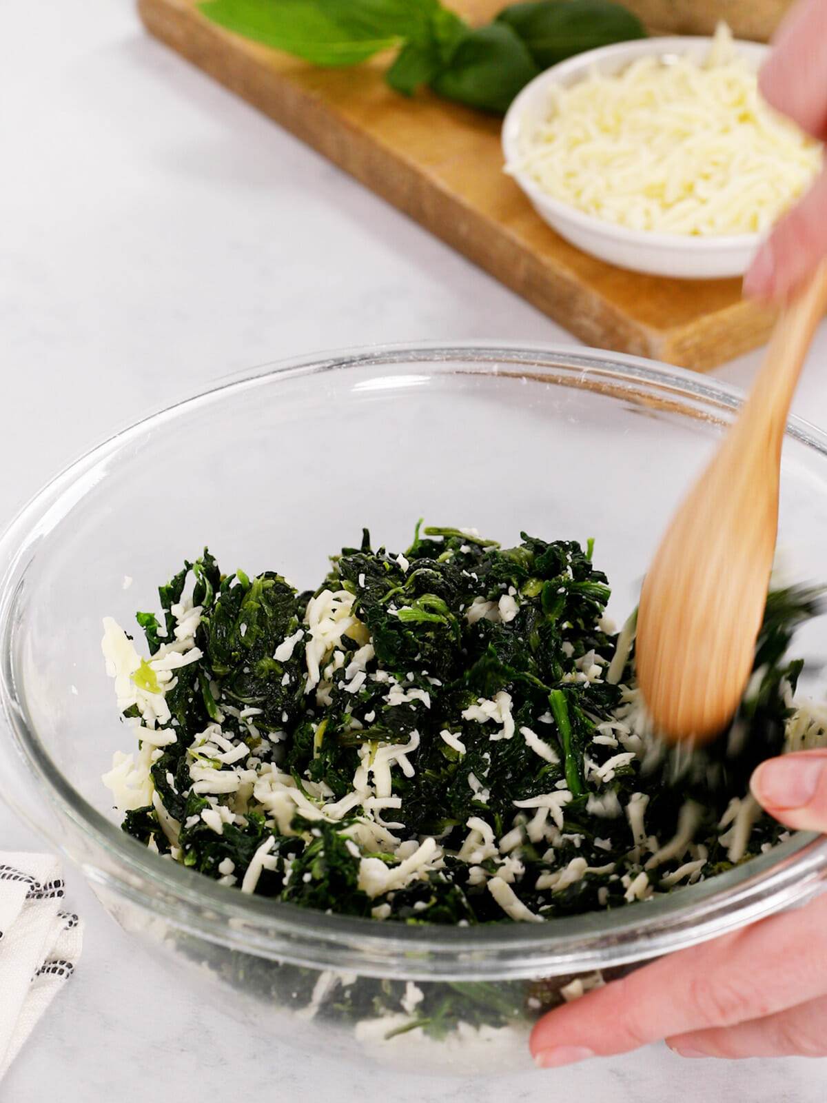 Mixing spinach and mozzarella cheese for a stuffed turkey meatloaf recipe.