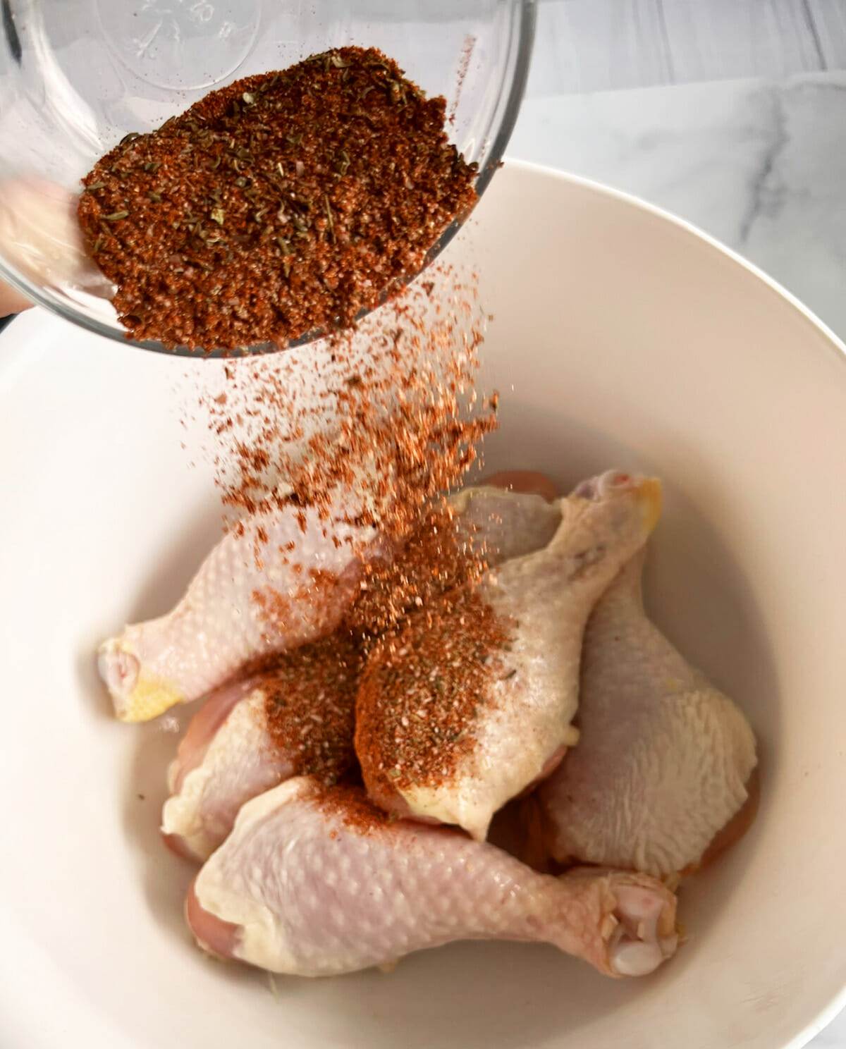 Seasoning chicken legs with blackened seasoning.