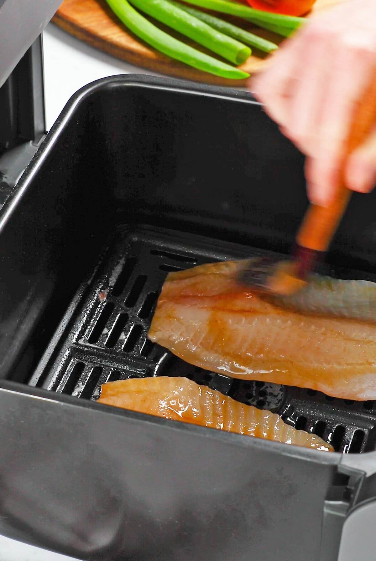 Brushing teriyaki sauce on tilapia filets for our air fryer tilapia recipe.