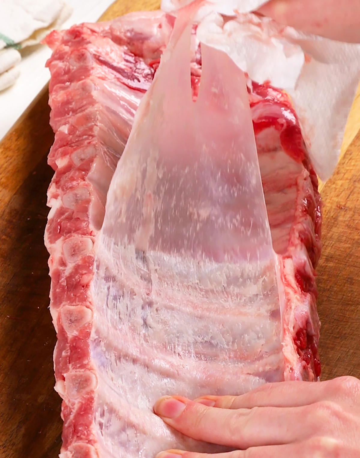 Peeling the membrane from a slab of ribs to be made in the oven.