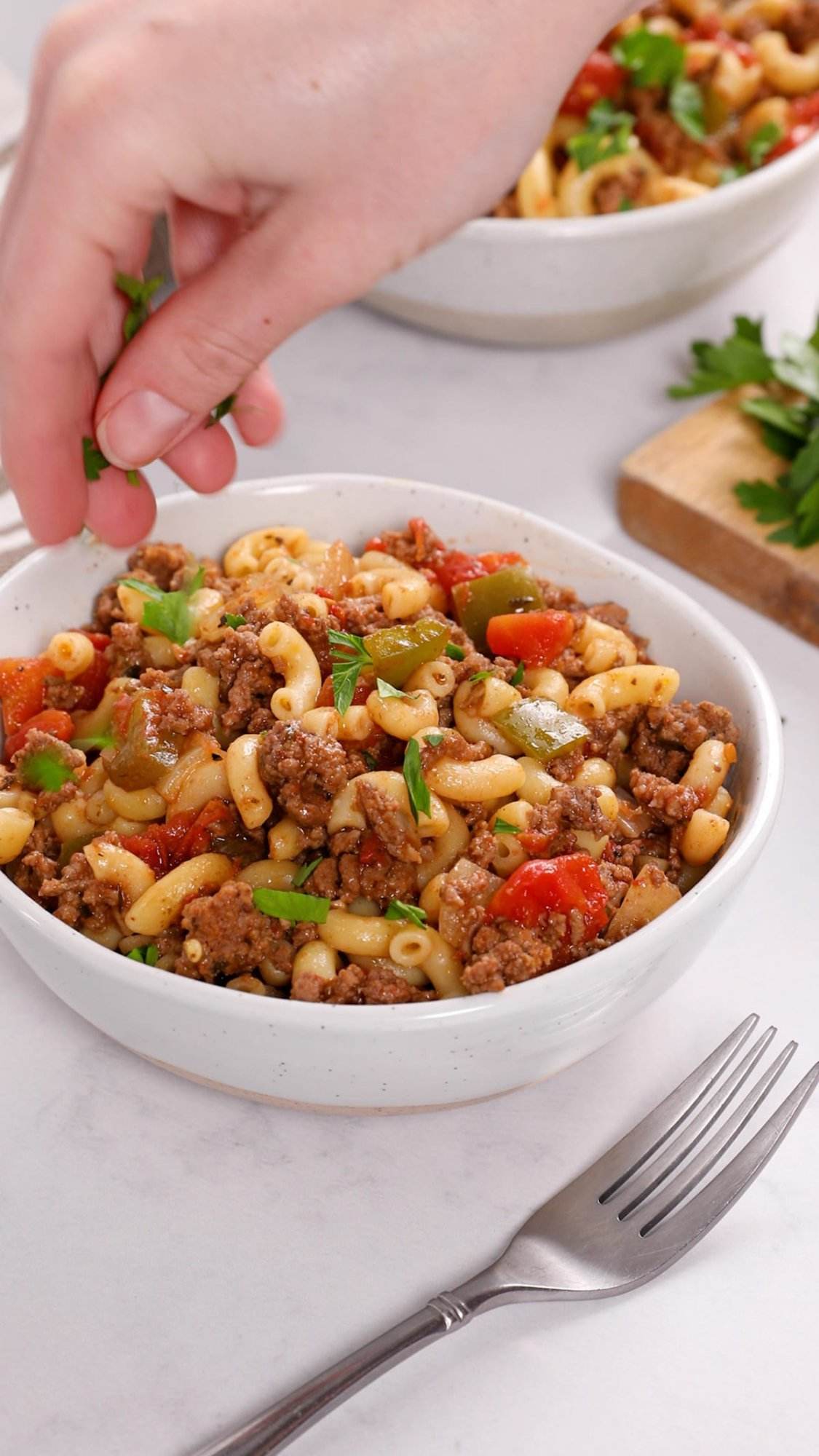 Serving American goulash topped with chopped parsley.