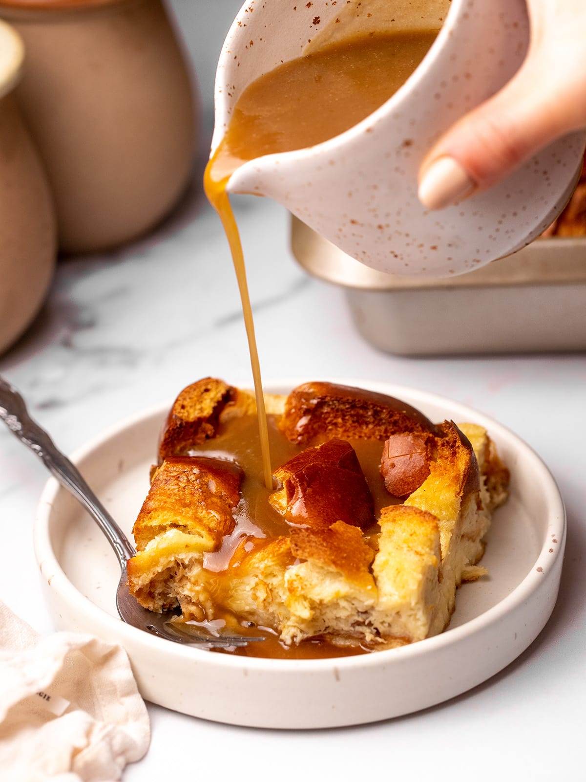 Pouring caramel sauce over homemade bread pudding.