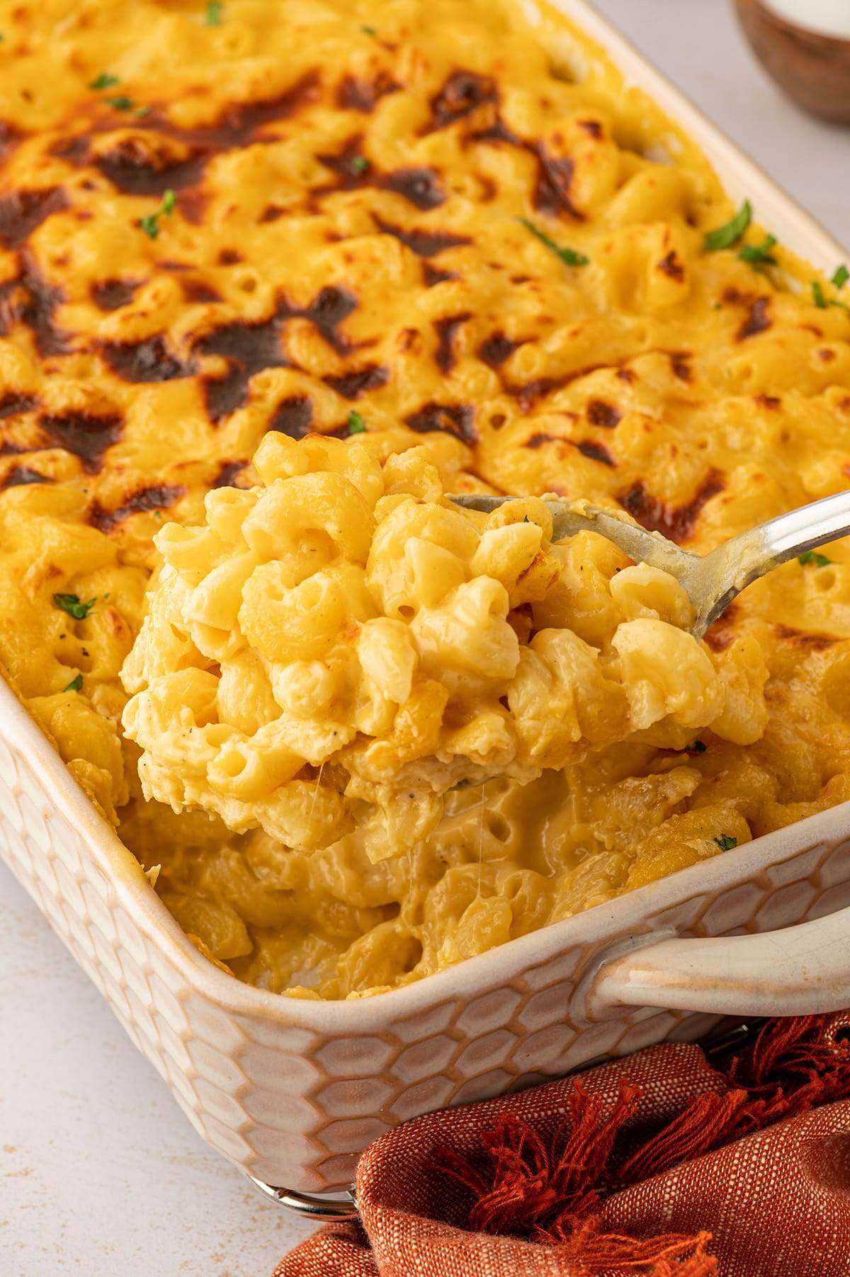 Baked mac and cheese being scooped out of the baking dish.