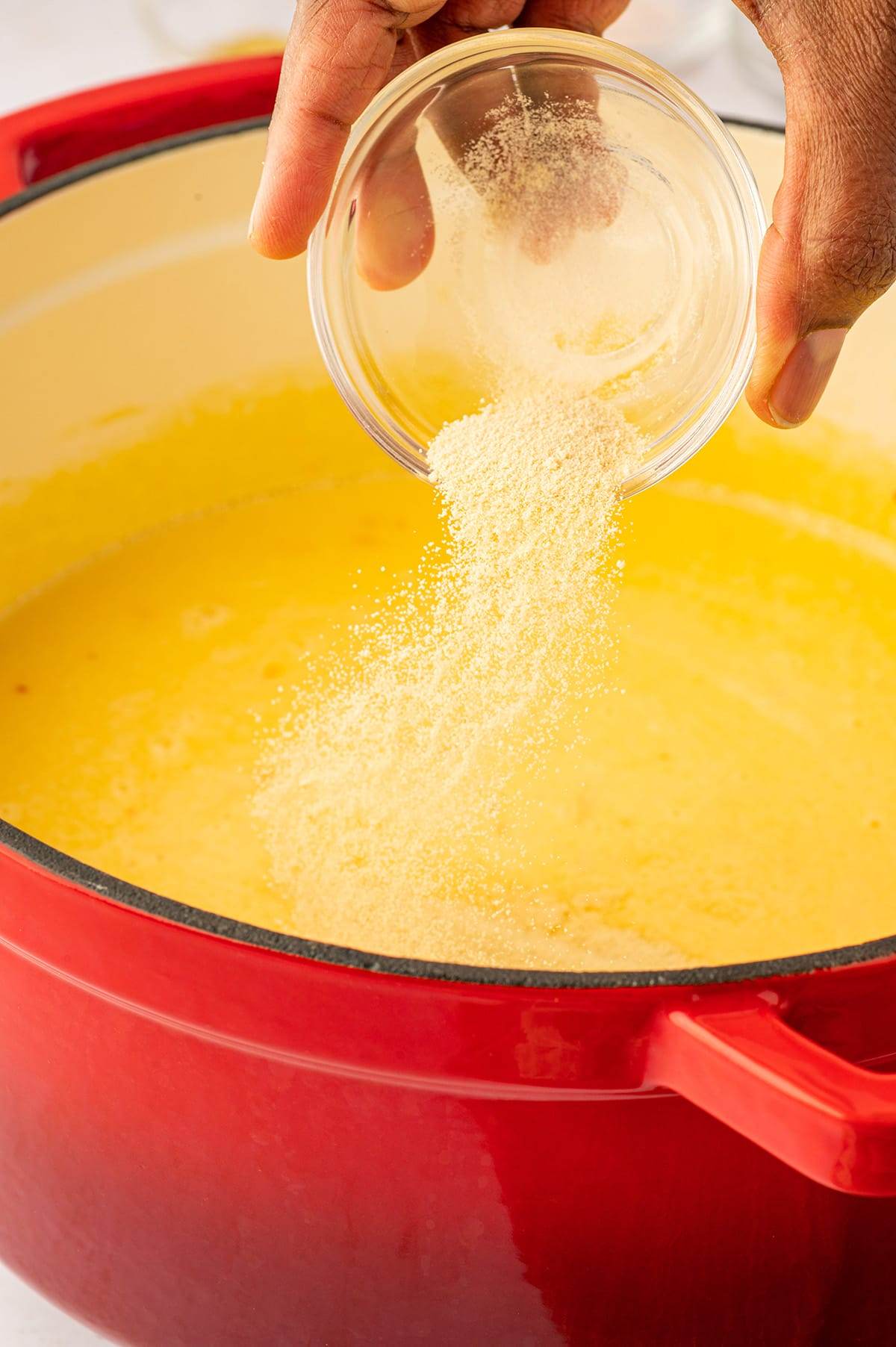 Adding the seasonings to cheese sauce for baked mac and cheese recipe.