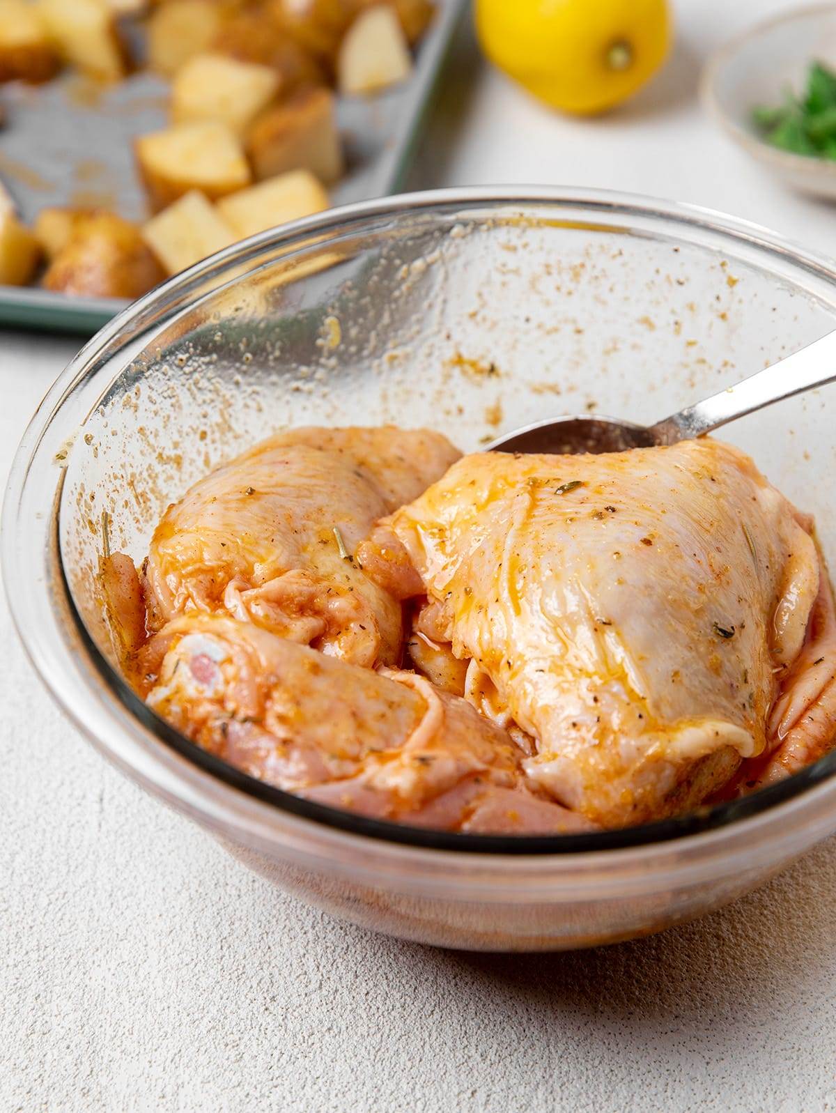 Adding lemon marinade to chicken thighs for a delicious sheet pan recipe.