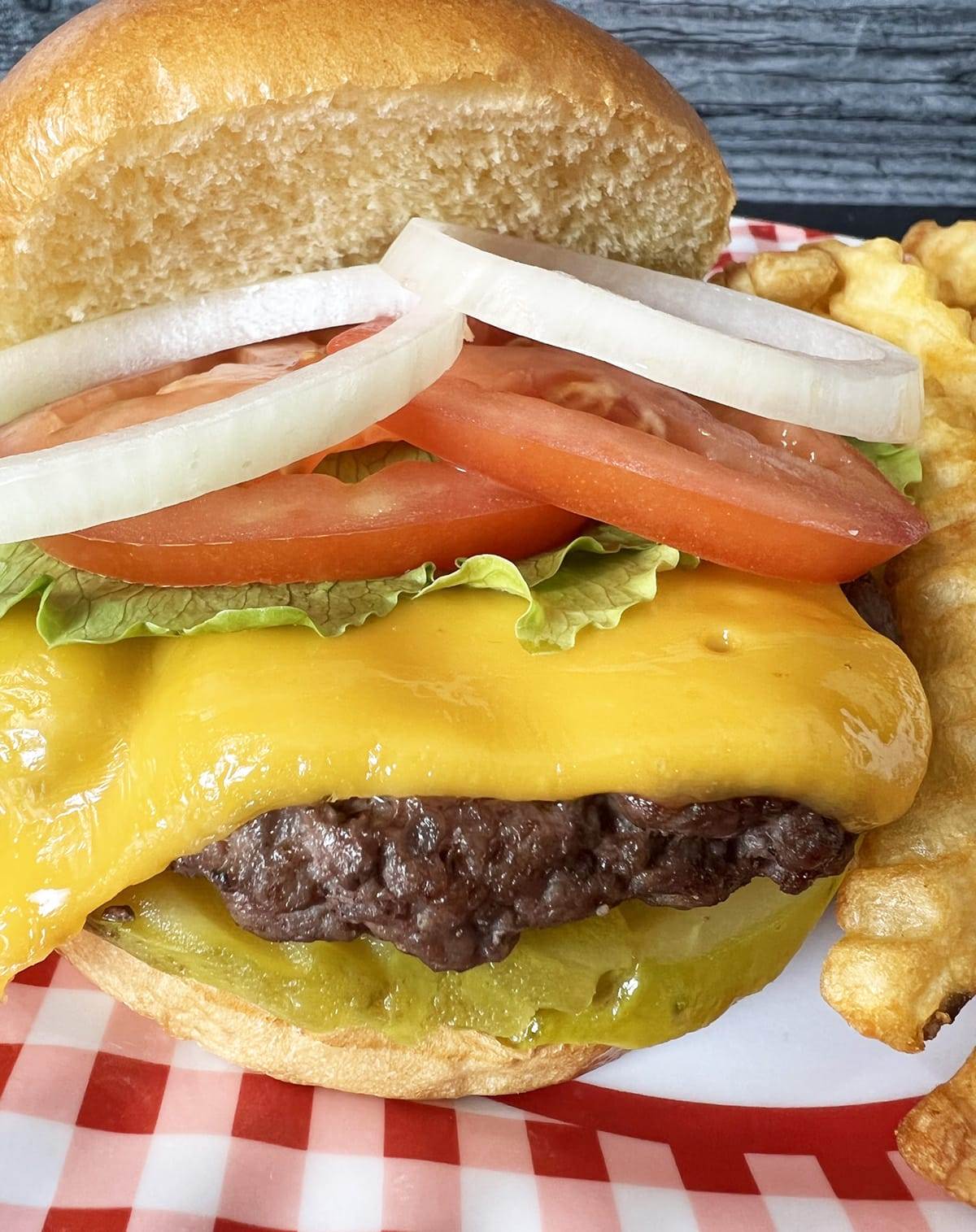 A cheeseburger made in an air fryer loaded with toppings on a fresh brioche bun.