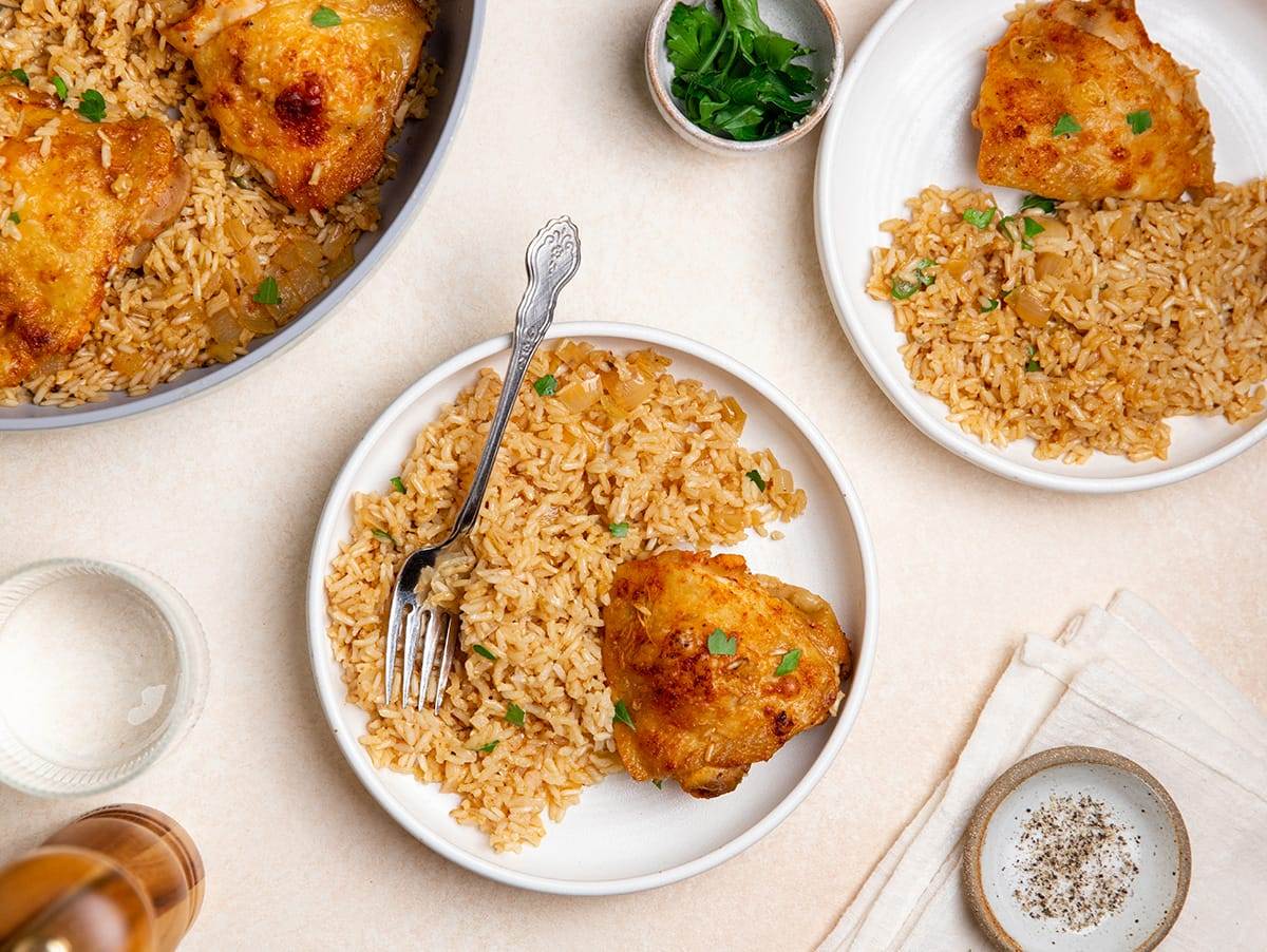 A plate served with chicken thighs and brown rice.