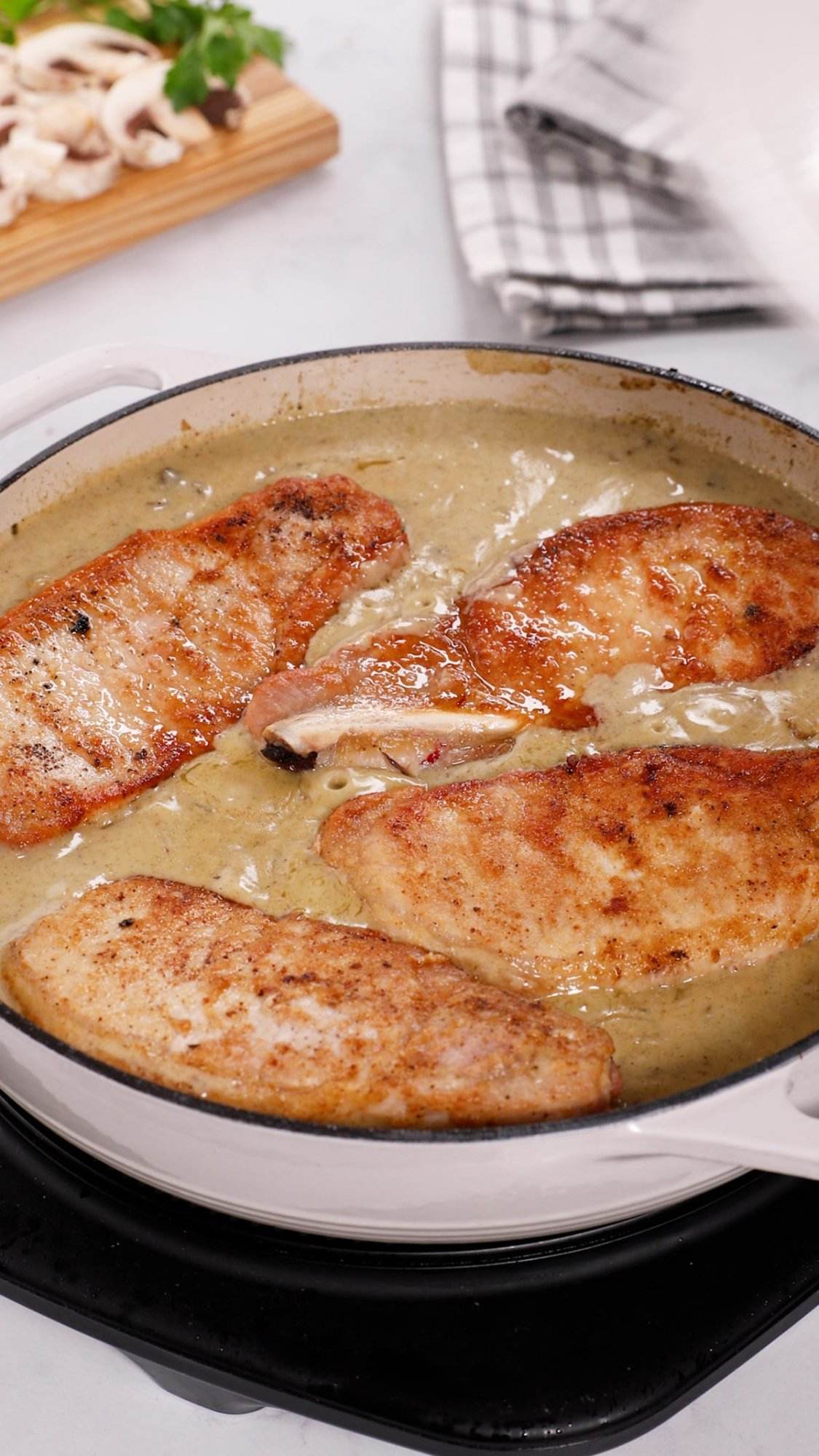 Pork chops nestled into mushroom onion gravy in a pan.