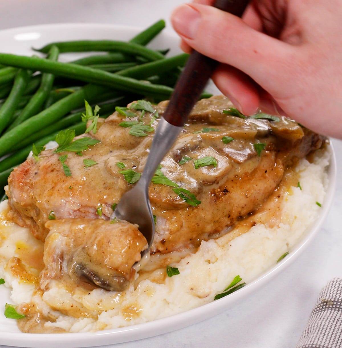 Using a fork to take a piece of smothered pork chop.