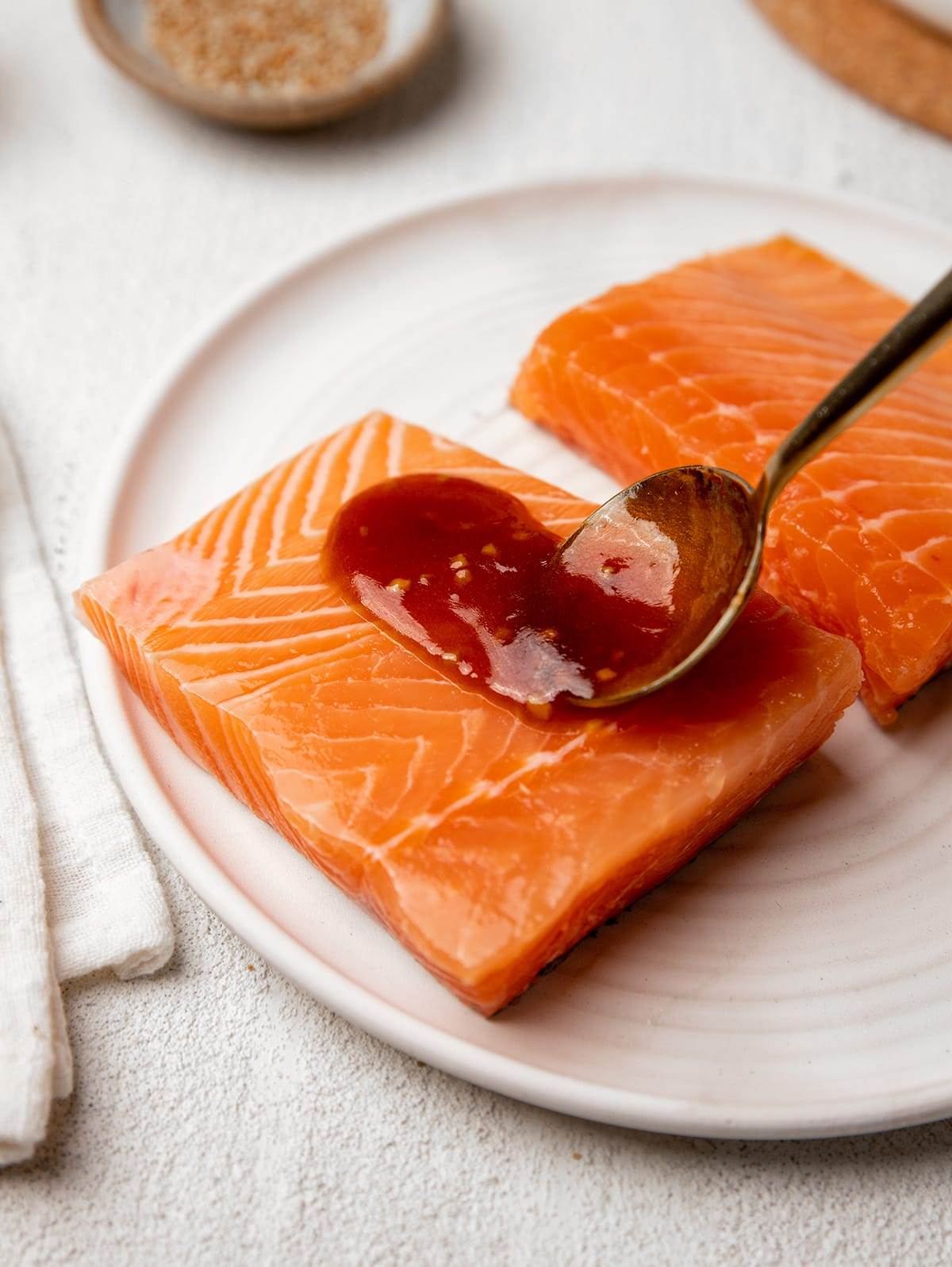 Spreading homemade teriyaki sauce on salmon filets.
