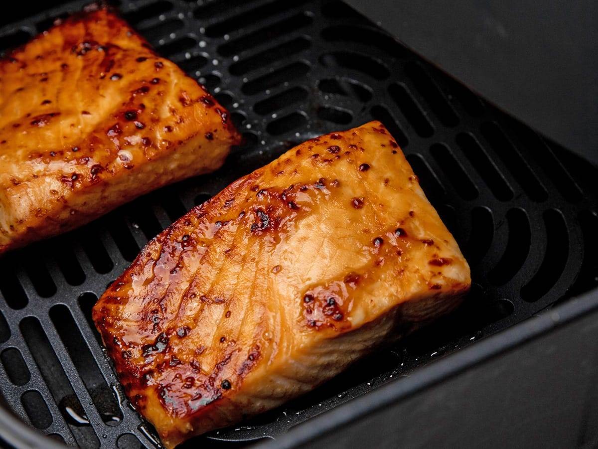 Salmon filets with teriyaki sauce cooking in an air fryer.
