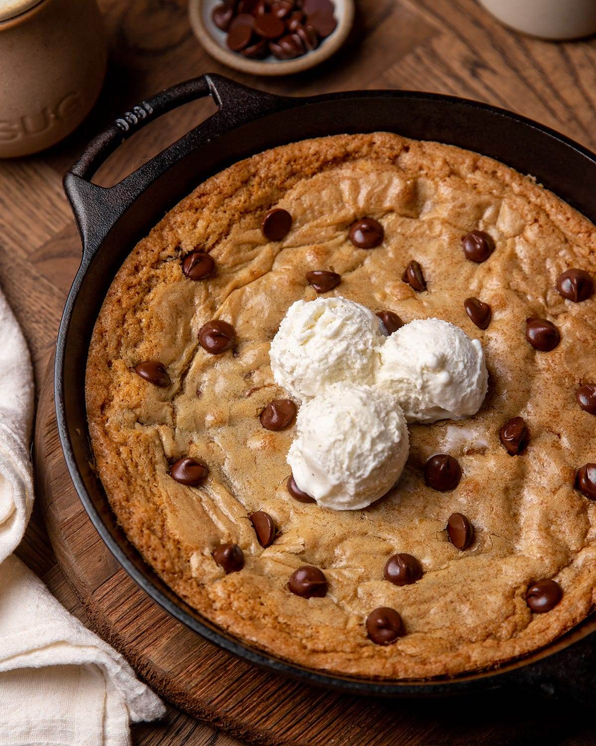 A giant chocolate chip cookie made in a cast iron skillet topped with ice cream.