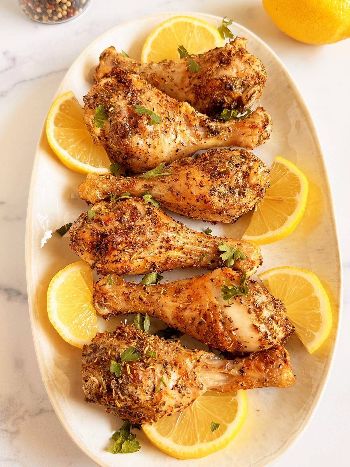 Chicken legs seasoned with Greek seasonings and cooked in an air fryer. Served with fresh lemon slices and topped with parsley.