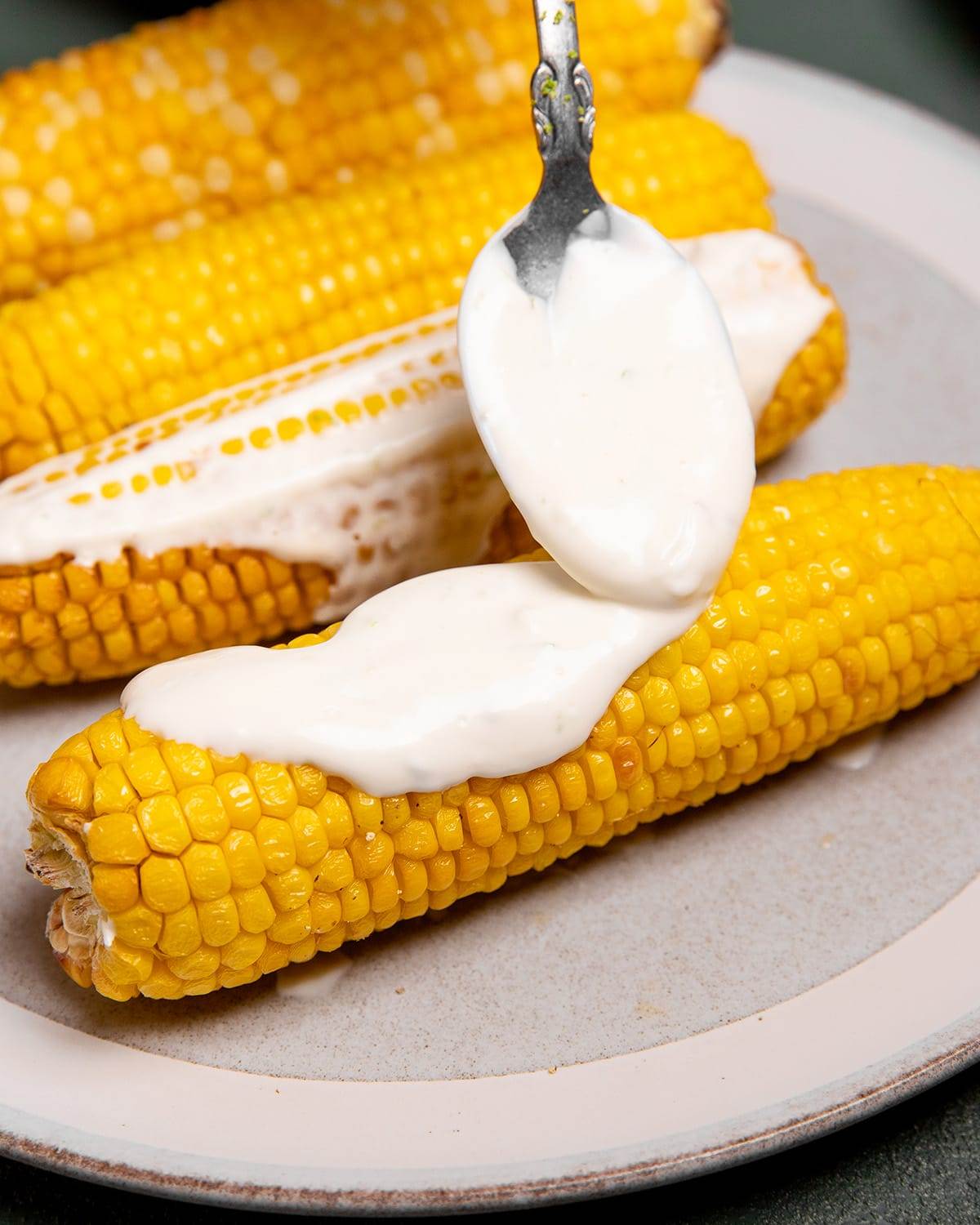 Adding the crema to air fryer roasted corn to make street corn.