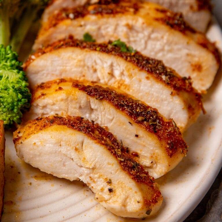 Oven baked boneless skinless chicken breast sliced up and served on a plate with broccoli and potatoes.