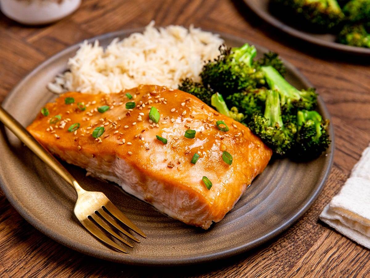 Sheet pan miso salmon and broccoli with rice served on a plate and topped with sesame seeds and green onions.