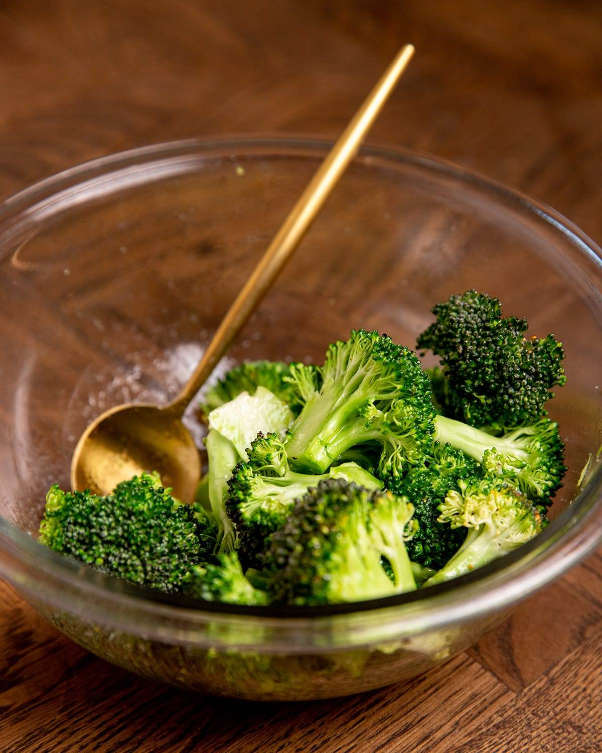 Seasoning broccoli to make sheet pan miso salmon and broccoli.