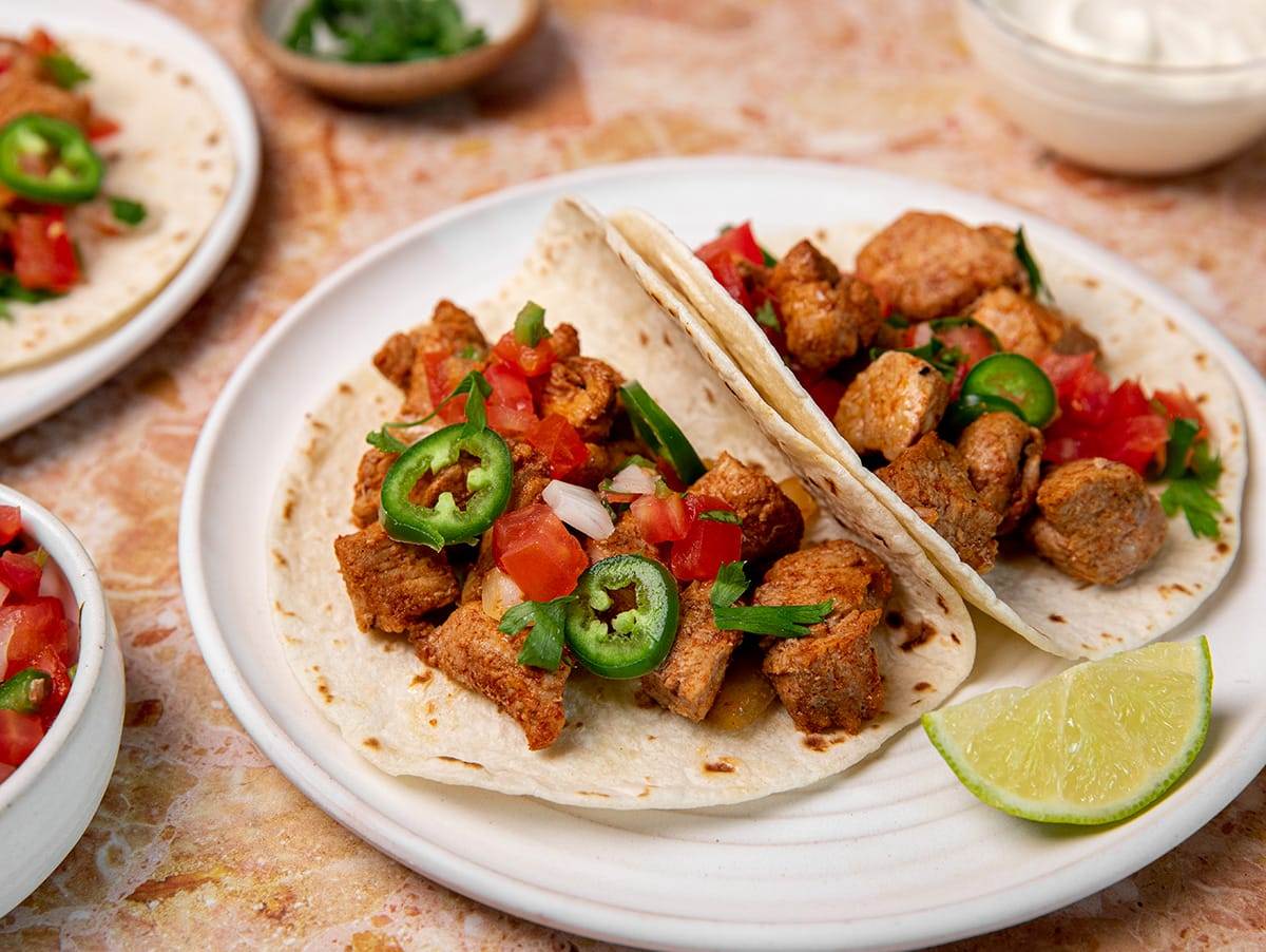 Delicious, seasoned chunks or pork tenderloin served in tortillas with fresh ingredients for pork tacos.